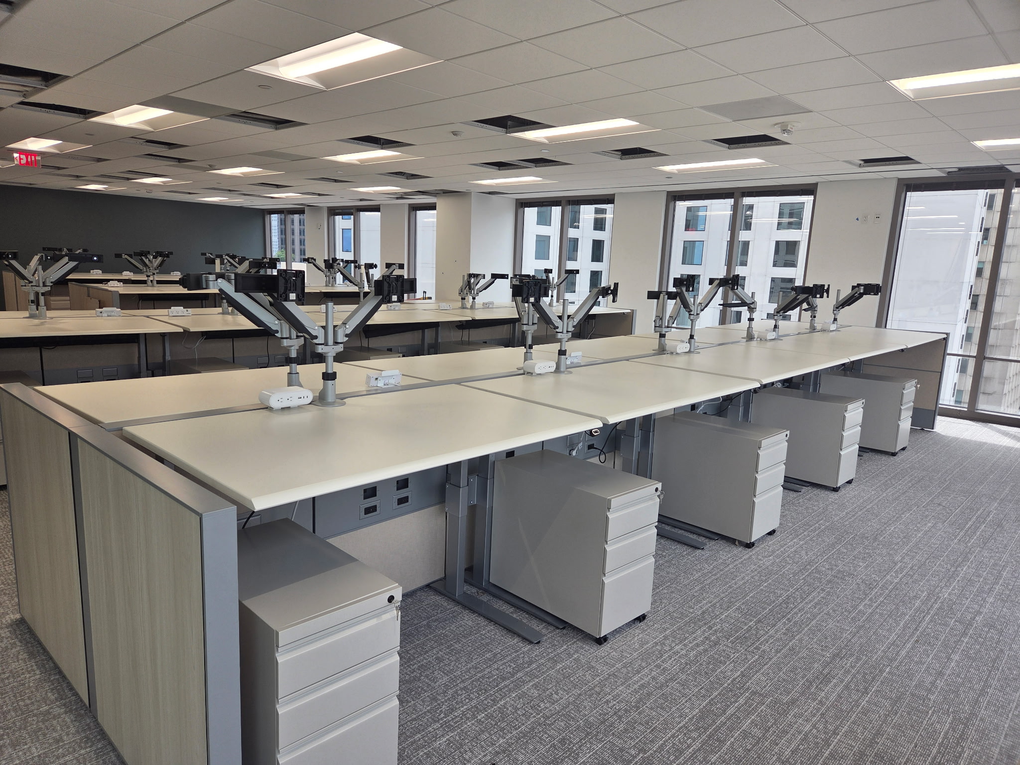 Rows of office workstations with monitor arms and pedestal storage
