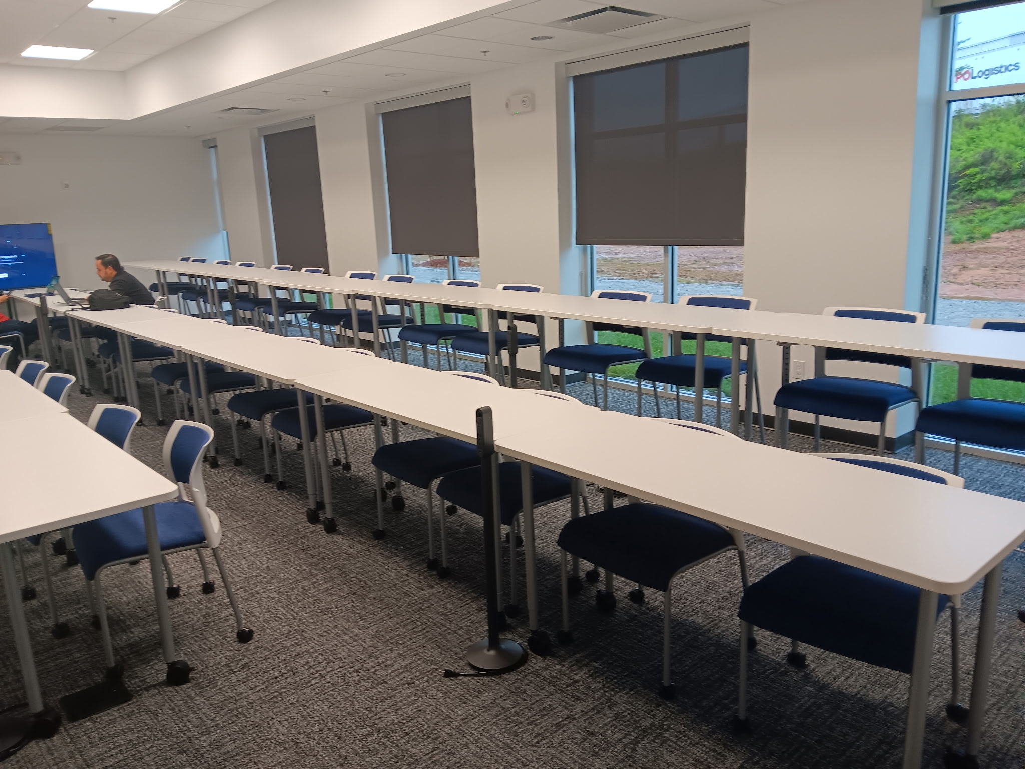 Classroom tables and chairs beside tall windows