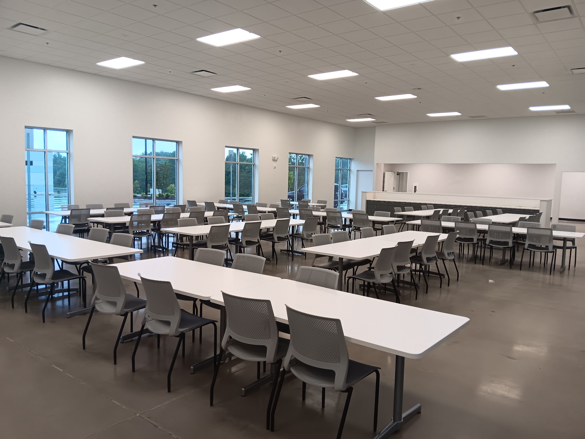 Rows of gray chairs and white tables in a multipurpose room